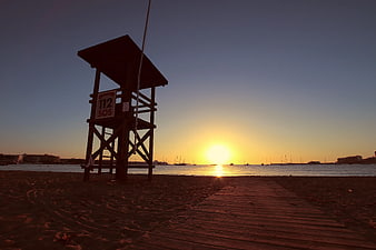 Silhouetted Lifeguard Tower on Beach at Sunset