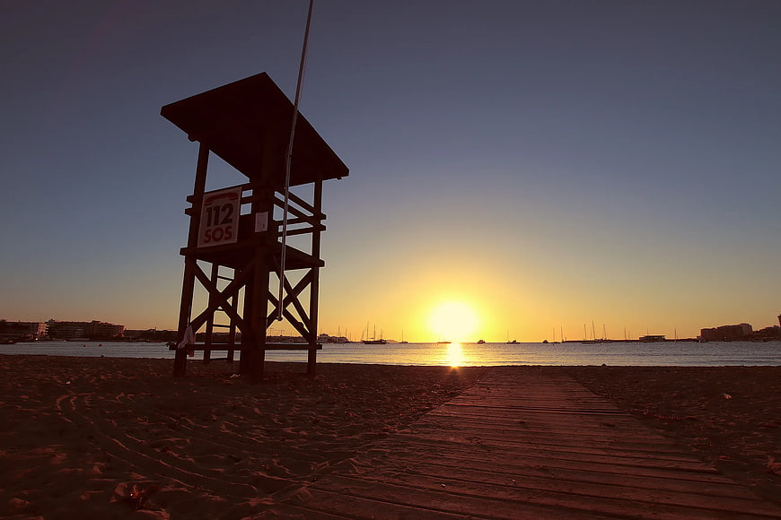 Silhouetted Lifeguard Tower on Beach at Sunset