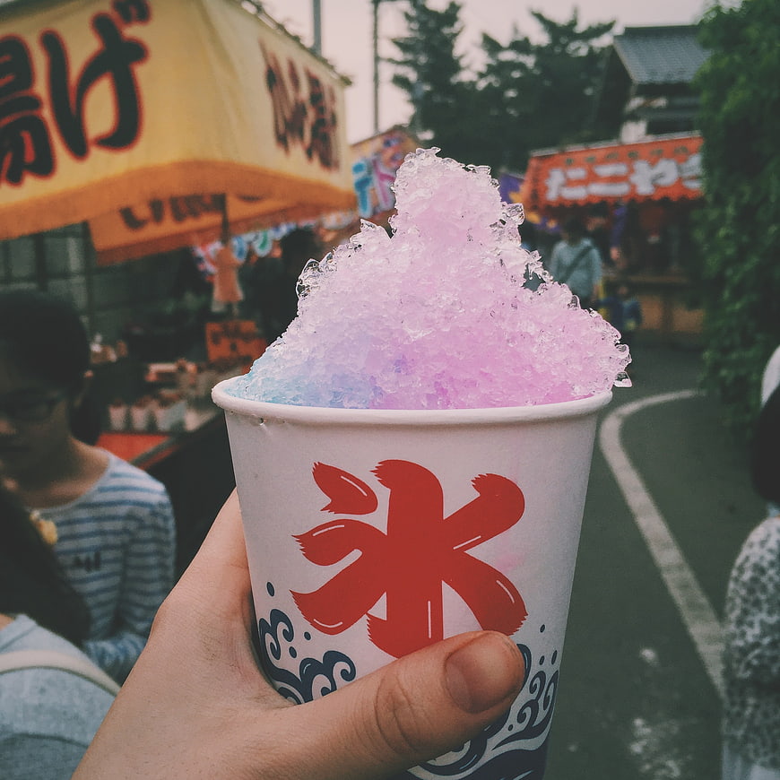Hand holding pink and blue shaved ice at Japanese festival
