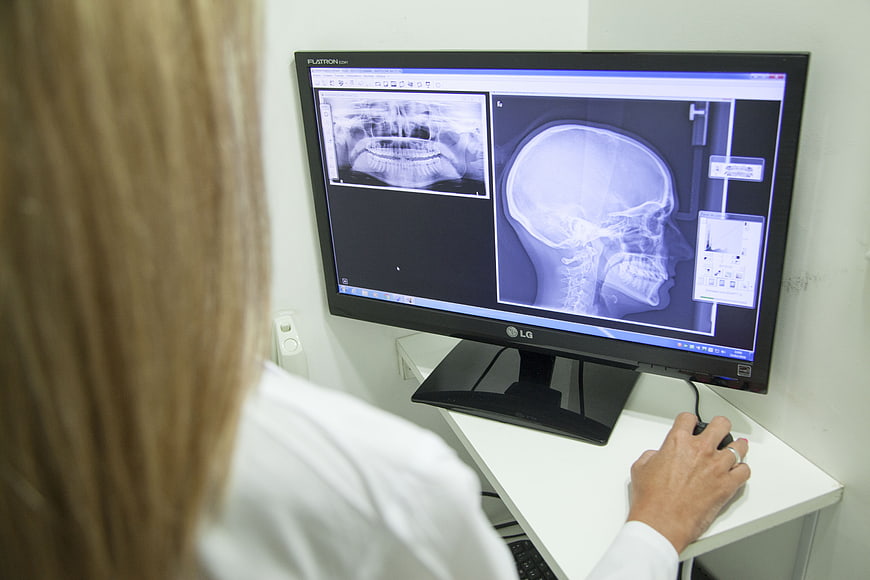 Dentist analyzing jaw X-ray on computer monitor