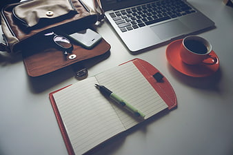 Flat lay of office desk with laptop, notebook, and coffee