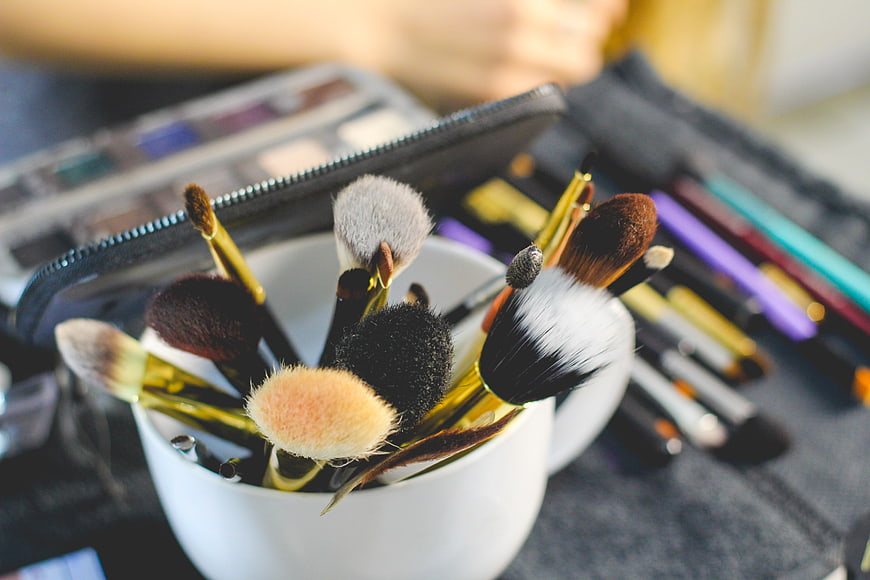 Makeup Brushes In White Cup With Cosmetics