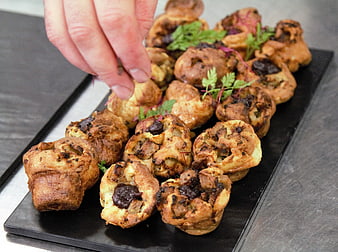 Chef garnishing savory Yorkshire puddings on black slate platter