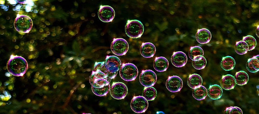 Colorful Soap Bubbles Floating Against Blurred Green Background
