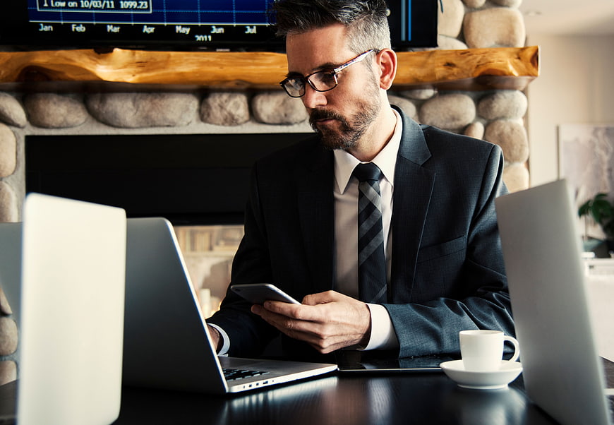 Businessman in Suit Using Smartphone at Desk