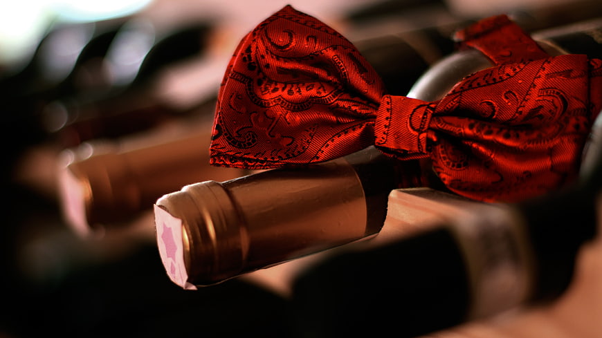 Red Wine Bottle With Red Patterned Bow Tie In Cellar
