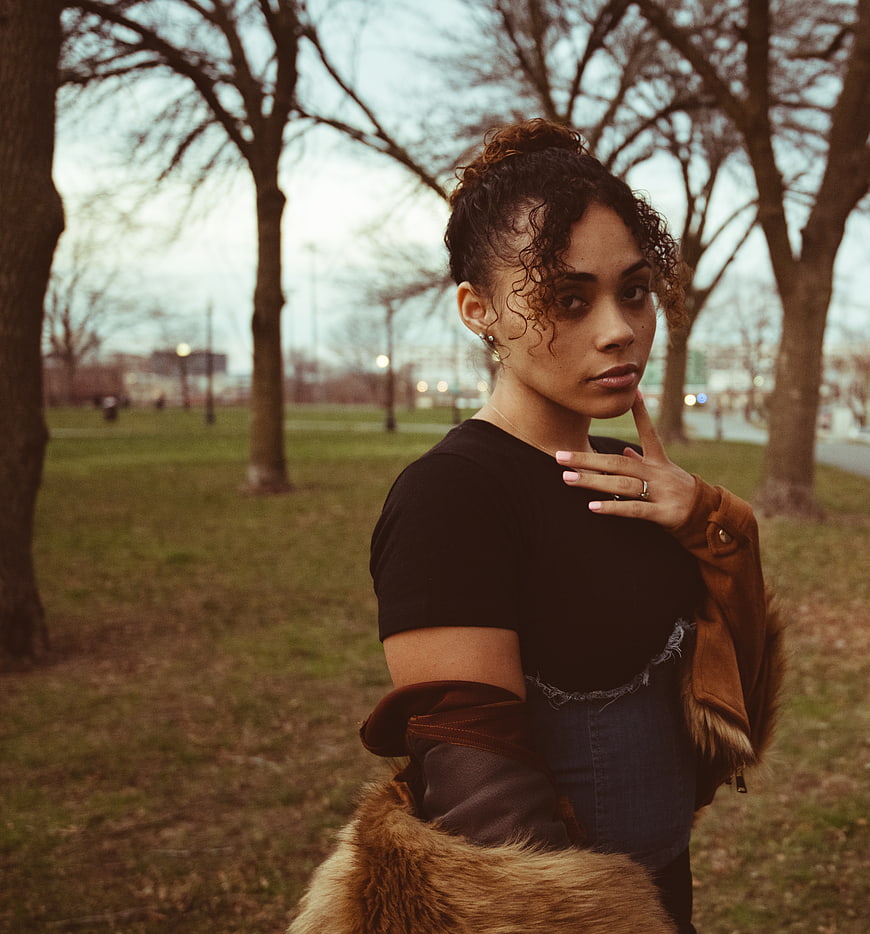 Young woman with curly hair in park wearing fur jacket
