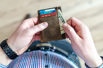 Man holding open leather wallet with cash and credit cards