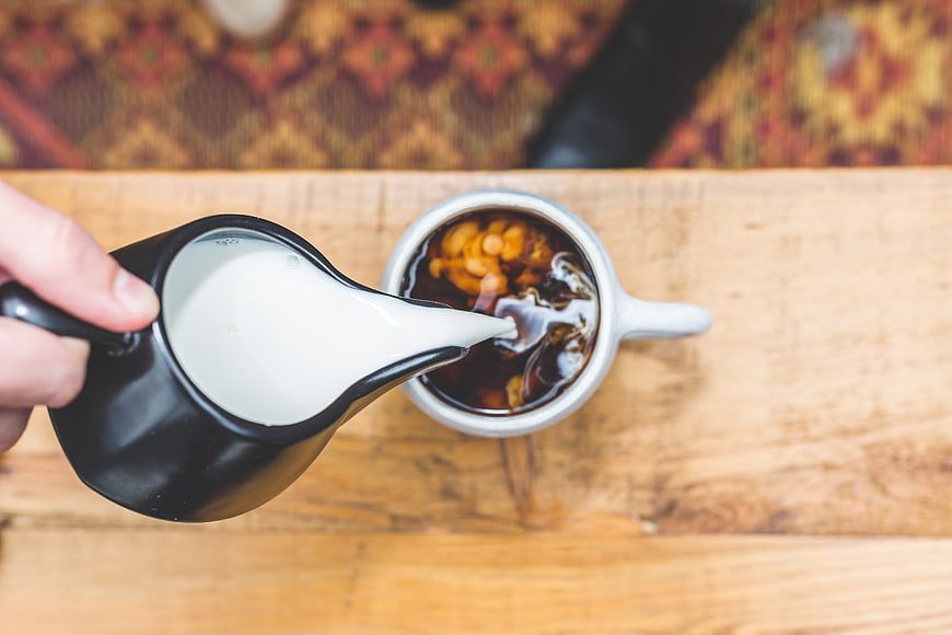 Top View of Milk Being Poured into Coffee Cup