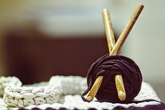 Close-up of wooden crochet hooks and dark yarn on white fabric