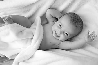 Smiling Newborn Baby Lying On Soft White Blanket Black And White Portrait