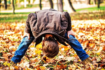 Toddler looking through legs in autumn leaves