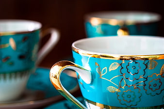 Close-up of turquoise teacup with gold floral pattern