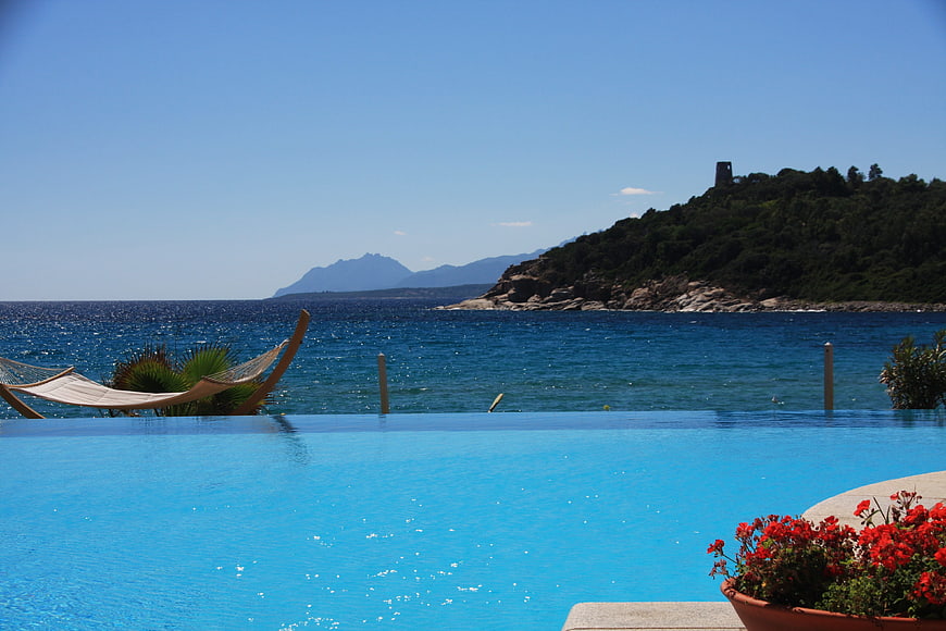 Infinity pool overlooking the sea with hammock and red flowers