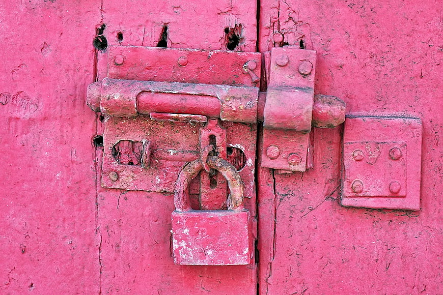 Rusty Red Padlock on Weathered Wooden Door