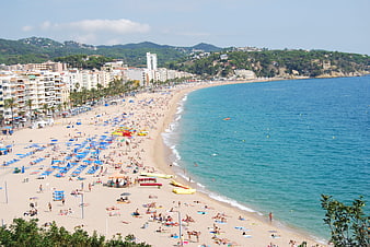 Panoramic View of Crowded Beach with Blue Umbrellas and Turquoise Sea