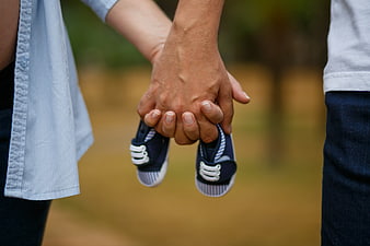 Couple Holding Hands With Baby Shoes