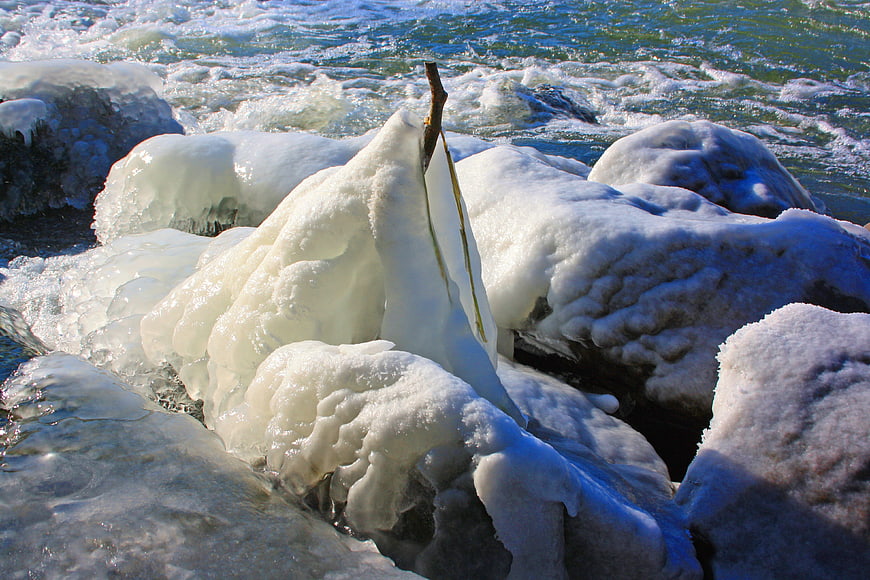Frozen Ice Formations on Rocks by Flowing River Water
