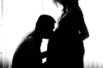 Silhouette of Father Kissing Pregnant Wife's Belly