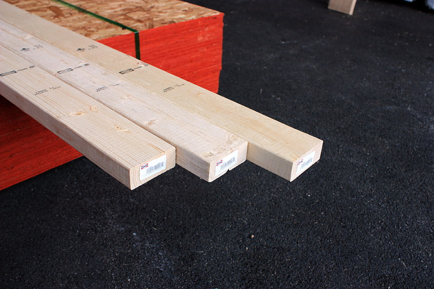 Stack of lumber planks on dark asphalt surface