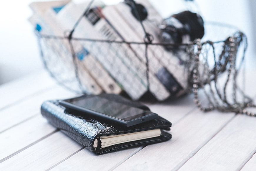 Black notebook and smartphone on white wooden table