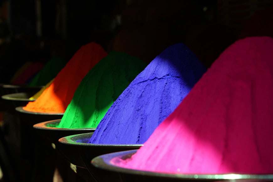Vibrant piles of colorful Holi powder in metal bowls