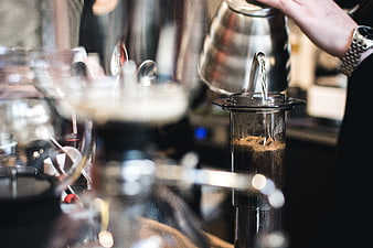Barista pouring hot water into AeroPress coffee maker