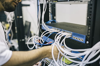 IT Engineer Connecting Network Cables in Server Rack