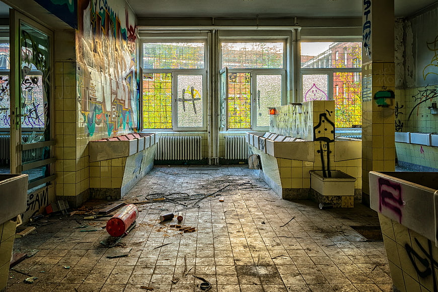 Abandoned tiled room with graffiti and debris