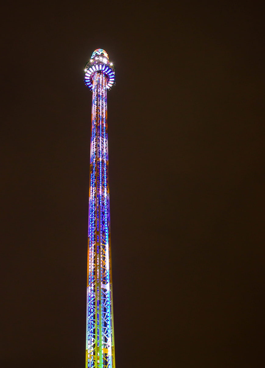 Illuminated Drop Tower at Night with Neon Lights
