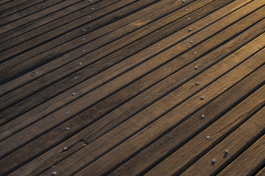 Diagonal wooden deck planks with metal screws texture background