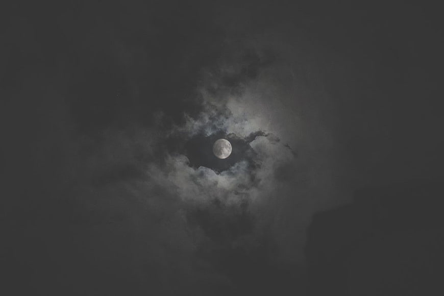 Full Moon Peeking Through Dark Clouds at Night