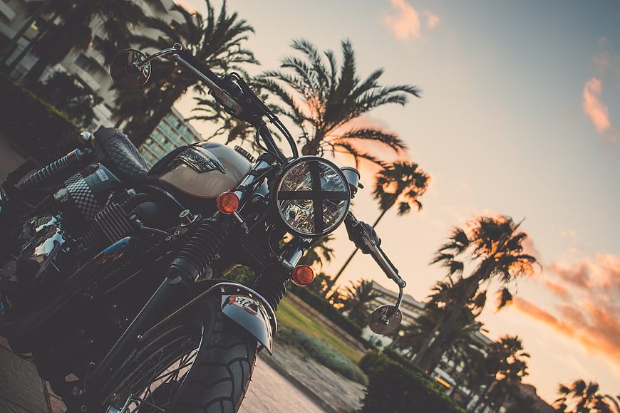 Retro Motorcycle Parked Near Palm Trees at Sunset