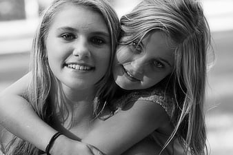 Black and white portrait of two smiling teenage girls hugging