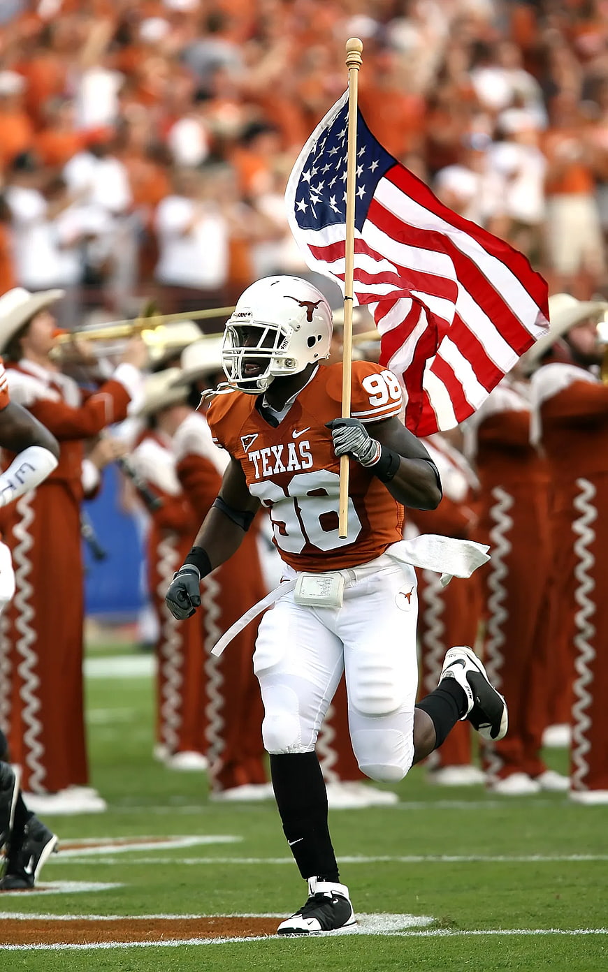 Texas football player running with American flag on field
