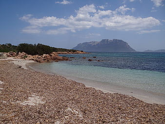 Secluded pebble beach with turquoise water and distant mountain