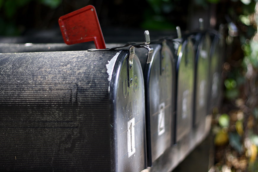 Row of black mailboxes with red flag raised