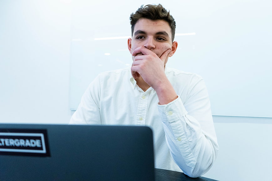 Young man thinking at laptop in modern office