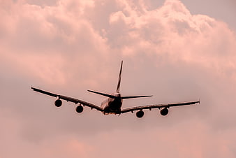 Four-engine airplane landing against pink sunset clouds