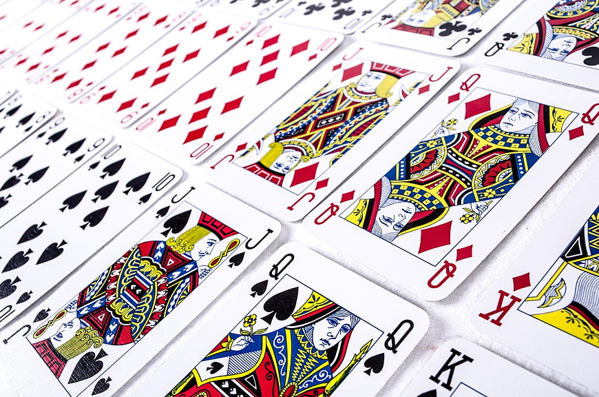 Close-up of playing cards arranged in a diagonal row on a white background