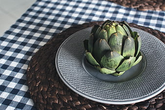 Fresh green artichoke on gray plate with checkered cloth