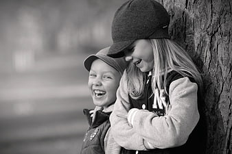Laughing children leaning against tree in black and white