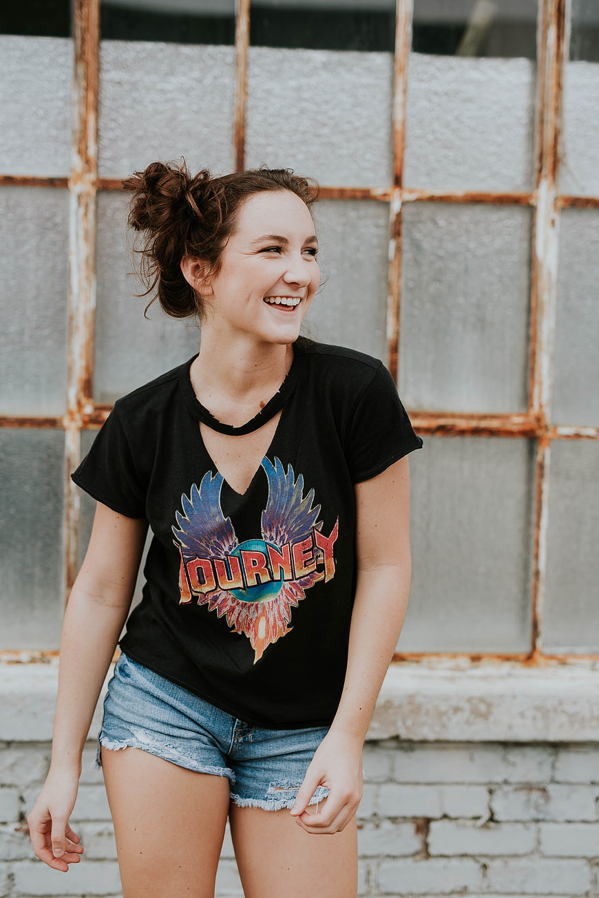 Happy woman laughing in black t-shirt and denim shorts
