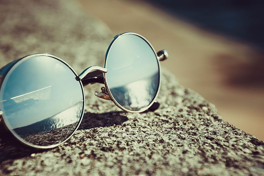 Round Sunglasses on Rock Reflecting Beach Ocean