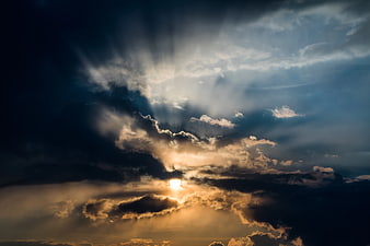 Dramatic sun rays breaking through dark storm clouds