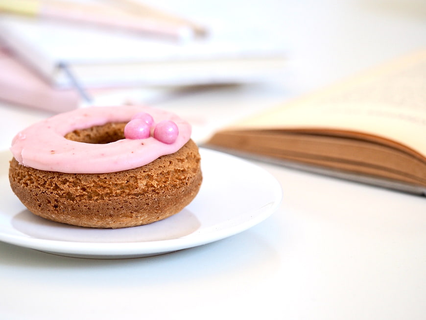 Pink Frosted Donut on White Plate with Open Book