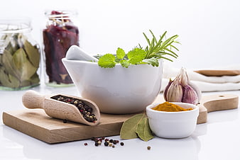 Fresh herbs and spices on wooden cutting board with mortar