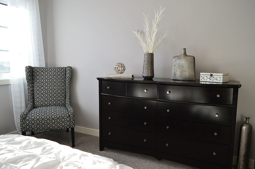 Modern Bedroom Interior with Black Dresser and Patterned Chair