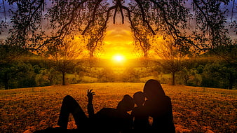 Silhouette of family relaxing in field at sunset