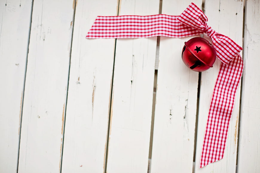 Red Christmas Bell with Gingham Ribbon on White Wood